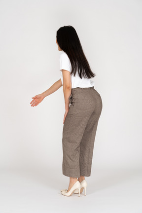 Side view of a young lady in breeches and t-shirt outstretching her hand and bending down