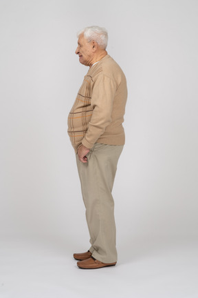 Вид сбоку на старика в повседневной одежде, стоящего с руками в карманах