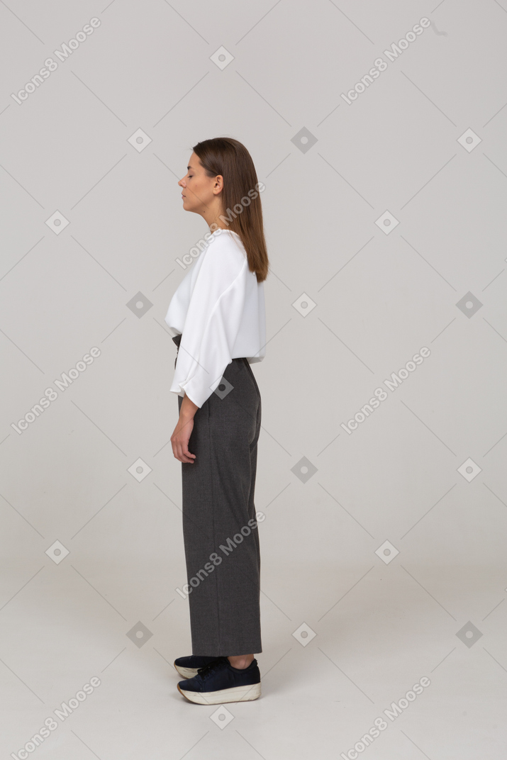 Side view of a young lady in office clothing standing with her eyes closed