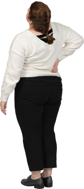 허리 통증으로 고통받는 흰색 스웨터에 플러스 사이즈 여자