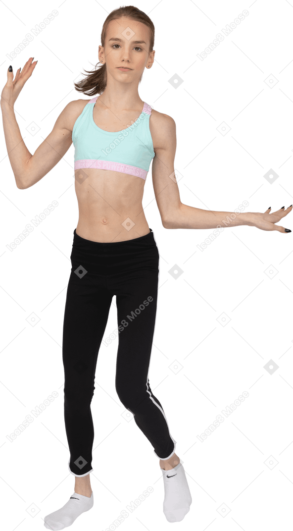 Vista frontal de una jovencita en ropa deportiva levantando las manos y bailando