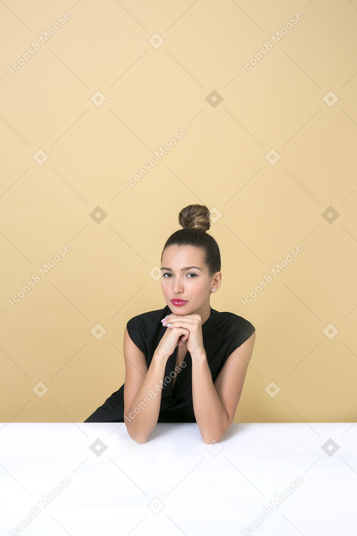 Young fashionable woman sitting at the table and leaning her face on hands