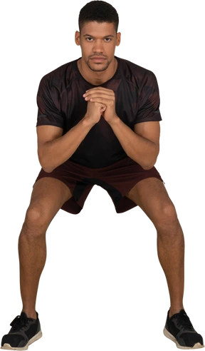 Young man in sports clothes squatting