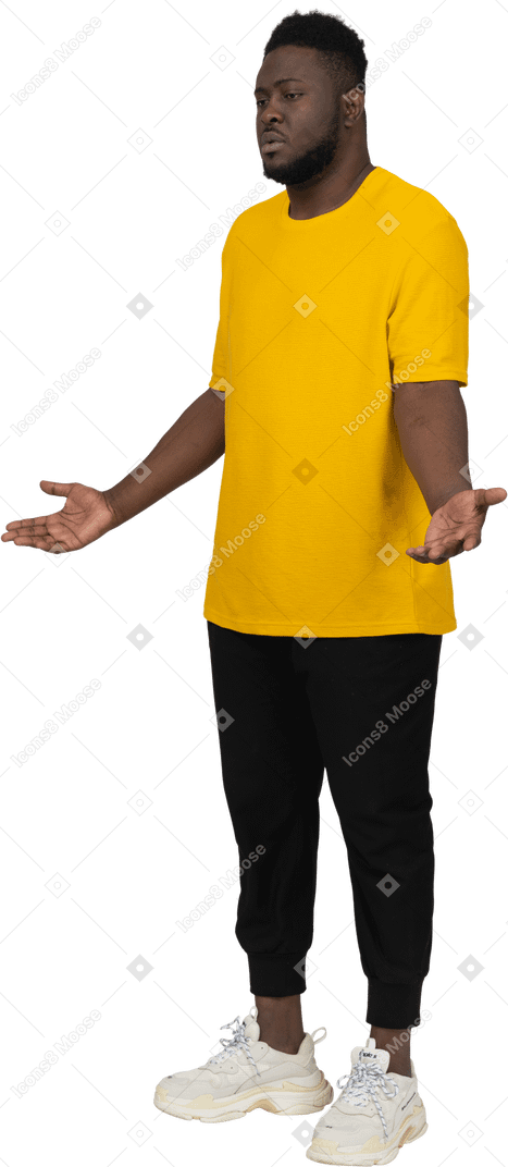 Vista di tre quarti di un giovane uomo dalla pelle scura dispiaciuto in maglietta gialla che allarga le mani