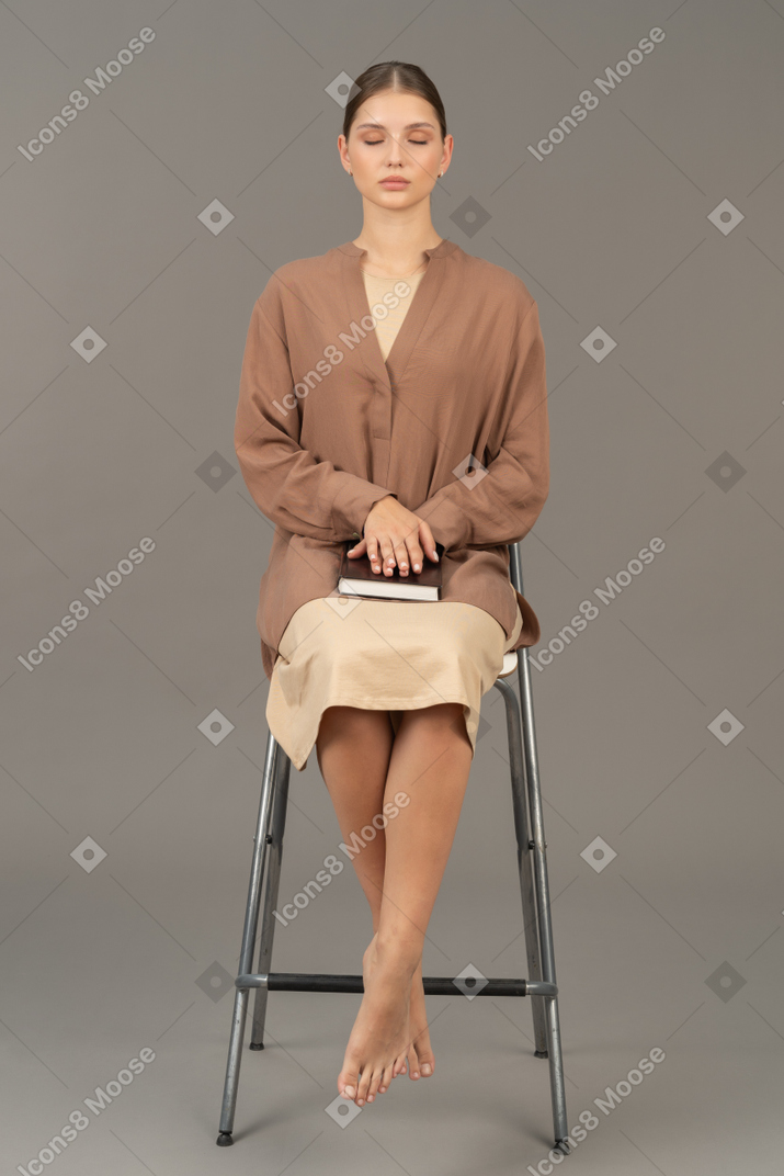 Young woman sitting on chair with a book