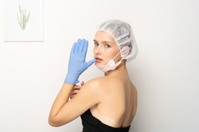Mujer joven con gorra quirúrgica levantando la mano