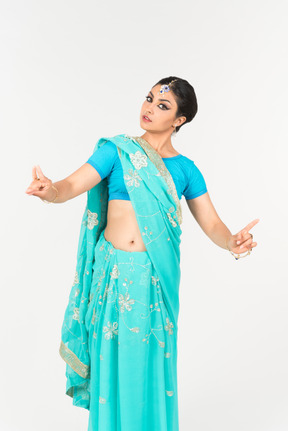 Joven mujer india en sari azul de pie en posición de baile