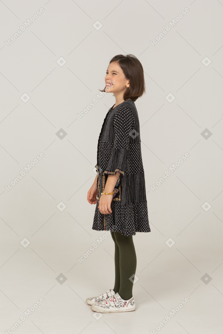 Vista lateral de uma menina sorridente com uma careta de vestido