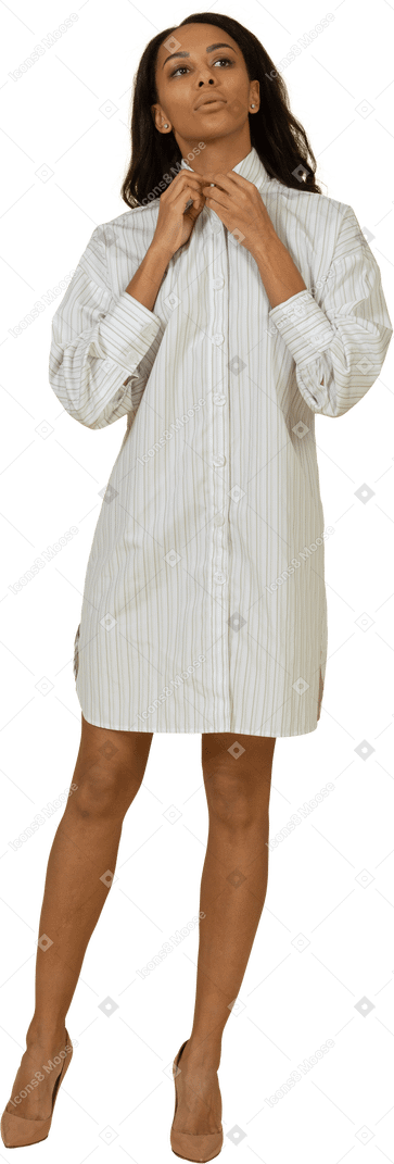 Vue de face d'une jeune femme à la peau foncée en robe blanche ajustant son col