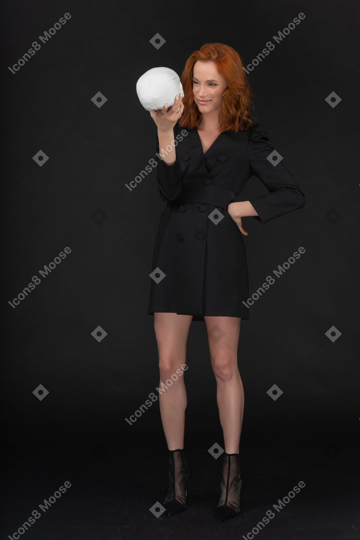 A frontal view of the elegant beautiful woman holding a skull and smiling peacefully
