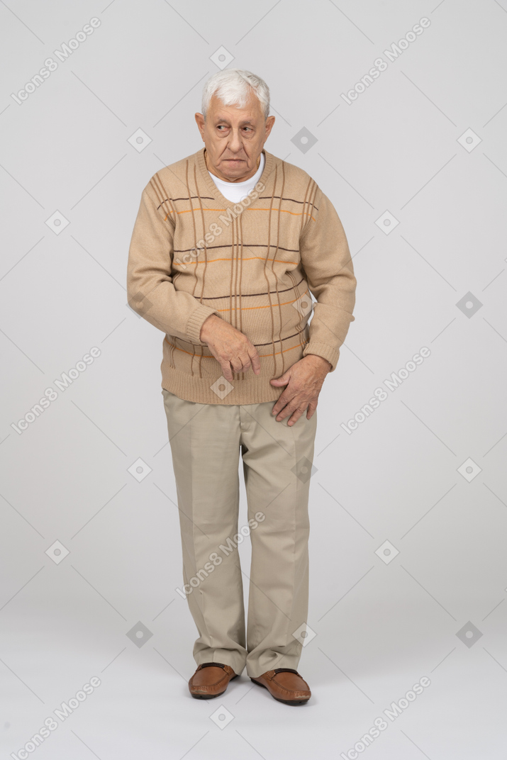 Front view of an old man in casual clothes looking at something with interest