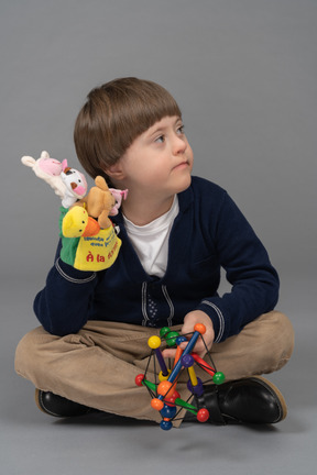 Kleiner junge sitzt mit gekreuzten beinen und hält spielzeug in der hand