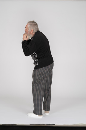 Rear view of old man with hands in mouth