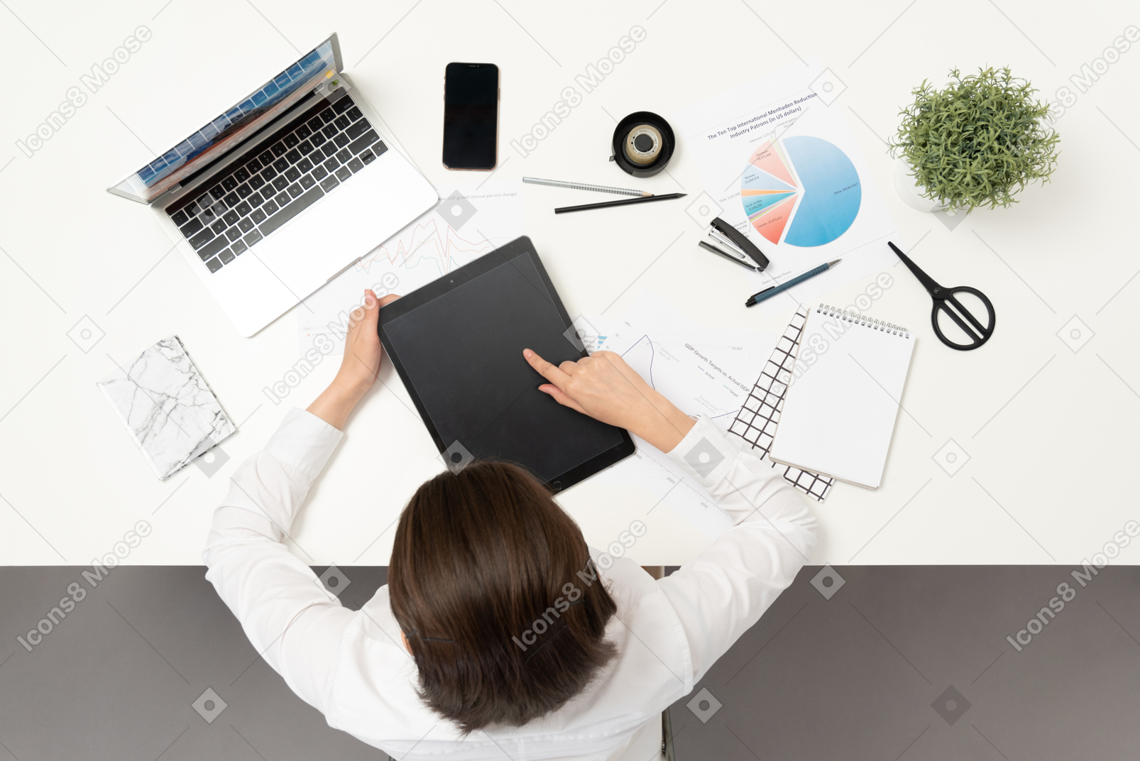 A female office worker at the table holding ipad