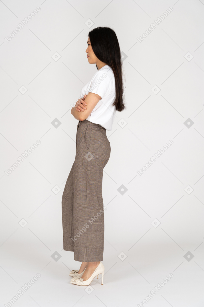 Side view of a suspicious young lady in breeches and t-shirt crossing hands