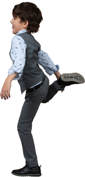 Vista laterale di un ragazzo in abito grigio in piedi su una gamba e che mostra la lingua