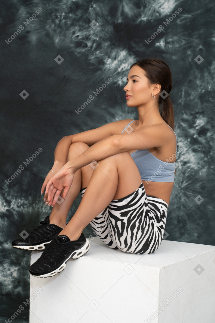 Colpo laterale di un atleta femminile che riposa su un cubo