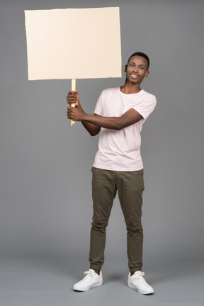 Um jovem alegre, segurando um cartaz em branco