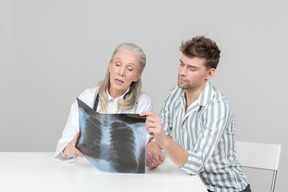 Doctora de edad explicando una radiografía a un paciente.