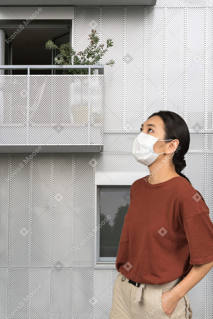 A woman wearing a face mask standing in front of a building