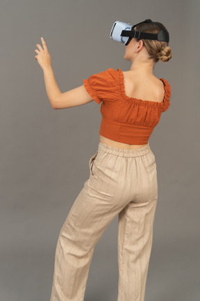 Three-quarter back view of young woman in vr headset