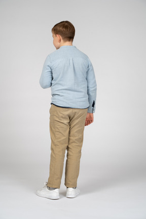 Rear view of a boy standing with hand on chest