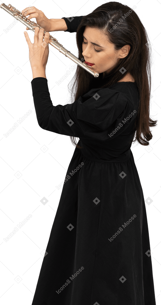Vue de trois quarts d'une jeune femme sérieuse en robe noire jouant de la flûte