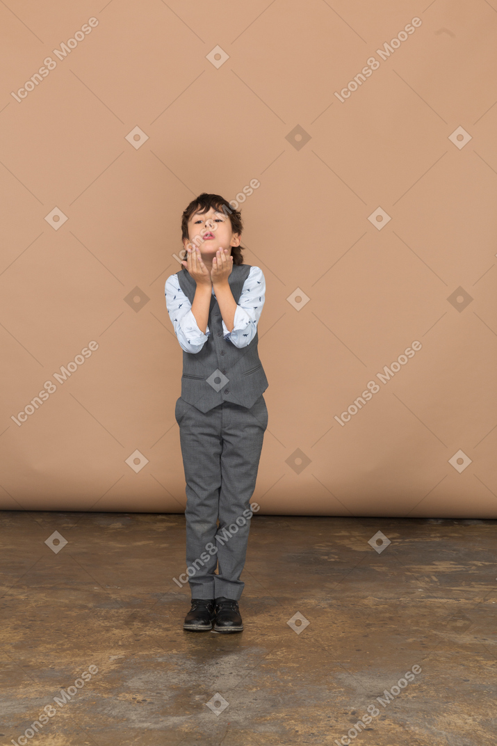 Front view of a boy in suit blowing a kiss