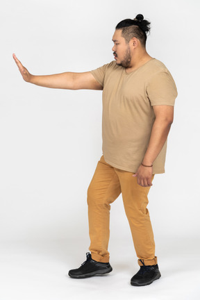 Serious asian man standing with outstretched hand making a stop gesture