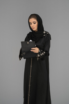 Mujer musulmana cubierta abriendo una bolsa