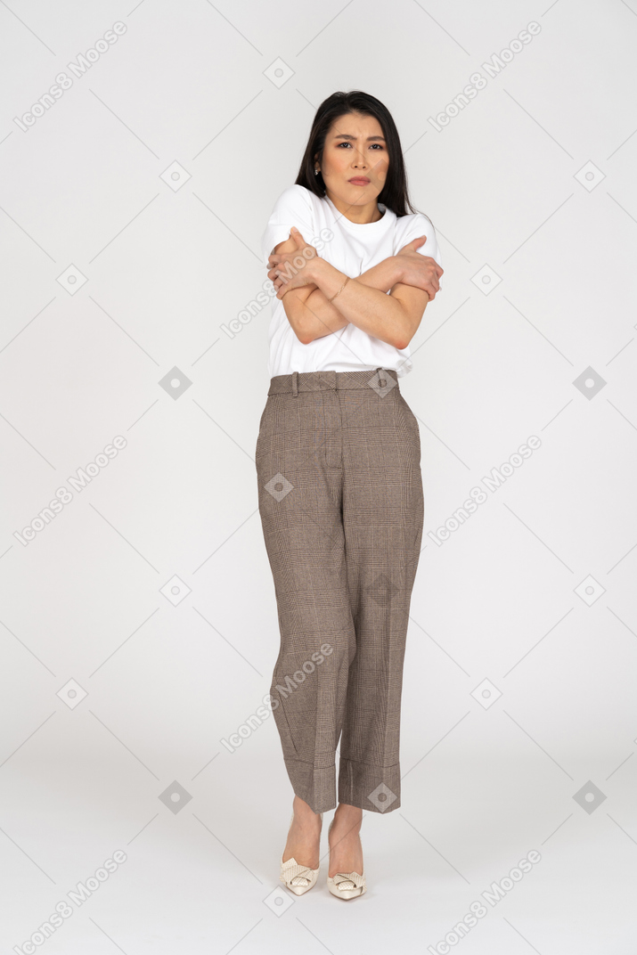 Front view of a young lady in breeches and t-shirt embracing herself