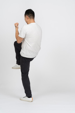 片足で立っているカジュアルな服装の男性の側面図