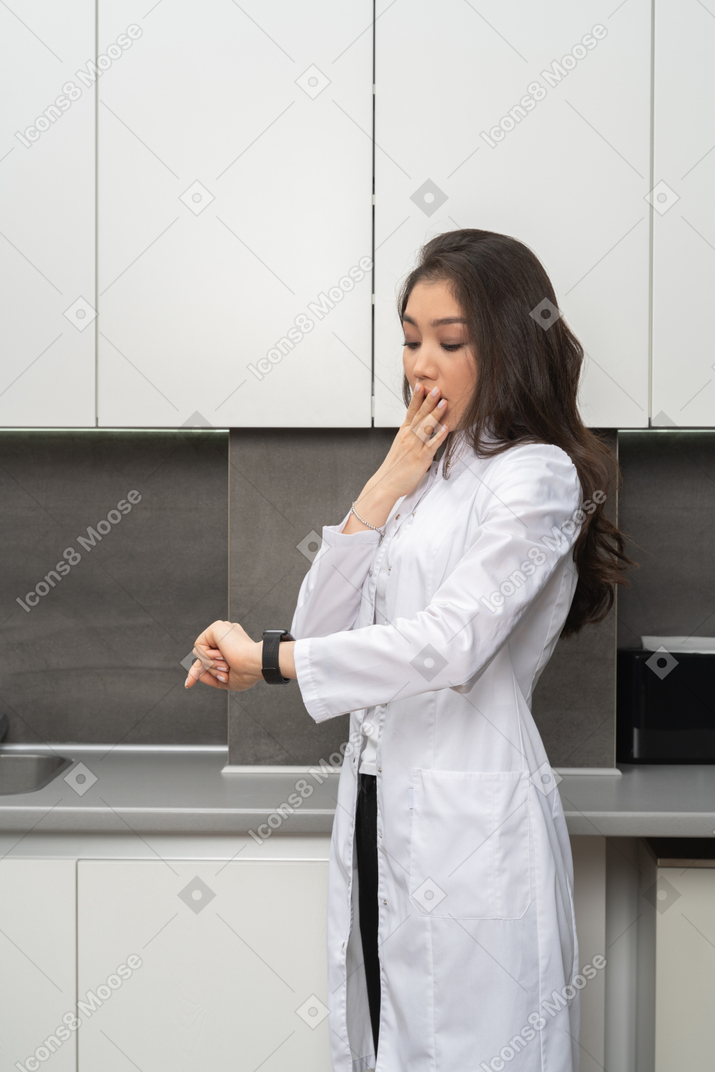 Удивленная женщина в белом халате проверяет время