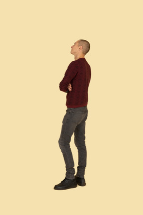 Back view of an offended young man dressed in casual clothes crossing his hands