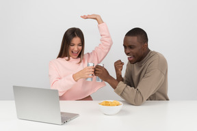 Pareja atractiva viendo un juego de deportes y bebiendo cerveza.