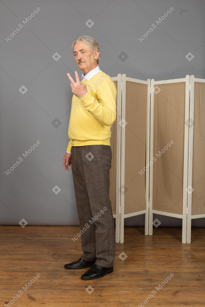 Vue de trois quarts d'un vieil homme montrant ses deux doigts