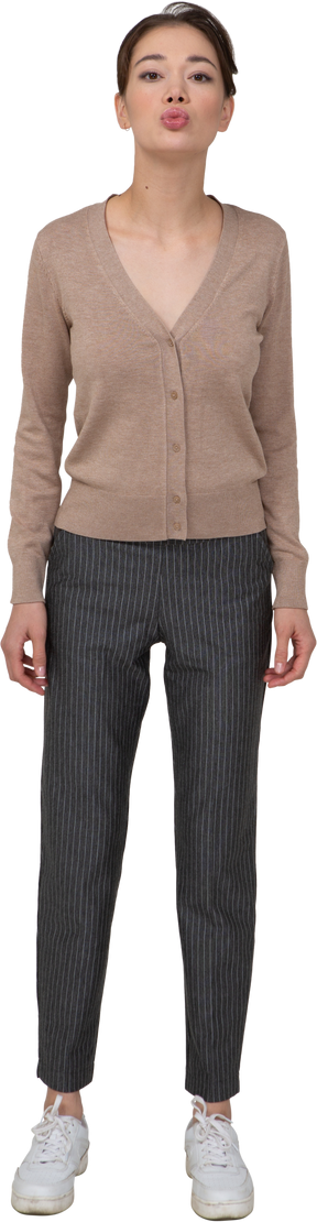 Vue de face d'une jeune femme boudeuse en pull et pantalon