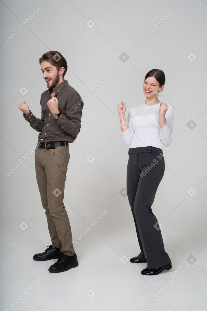 一对高兴的年轻夫妇穿着办公室服装的四分之三视图
