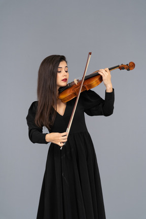 Close-up de uma jovem de vestido preto tocando violino