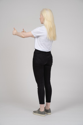 Vista traseira de uma jovem de pé com dois polegares para cima