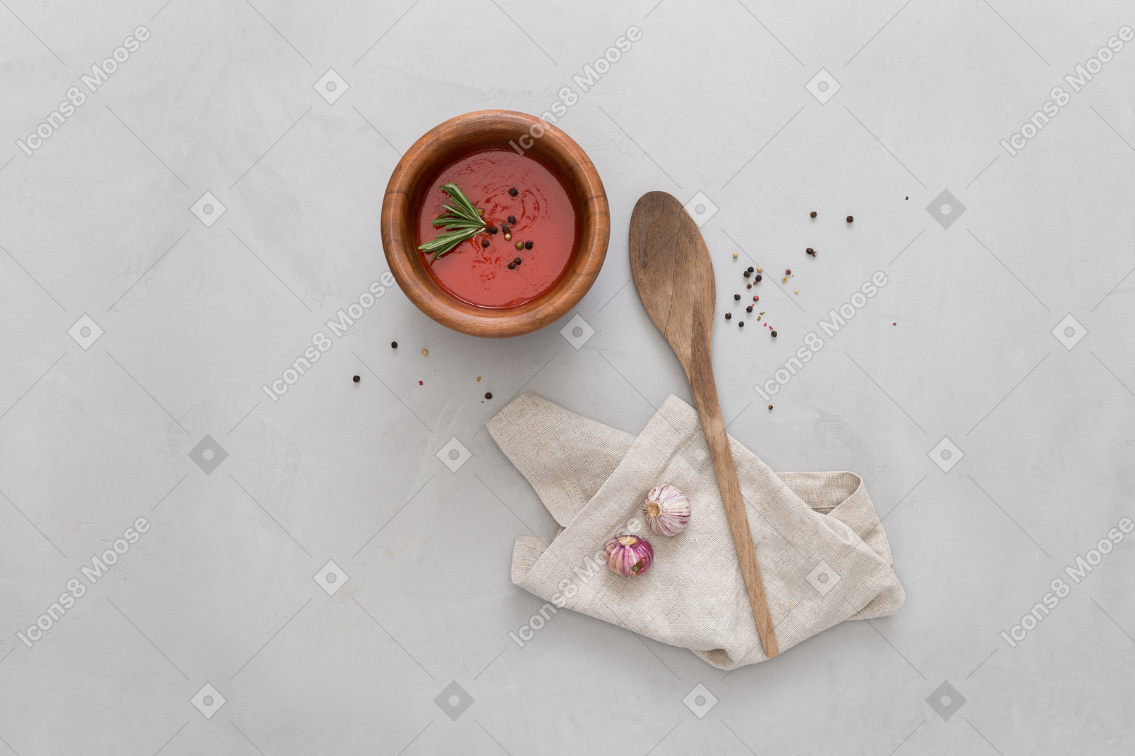 A bowl of gazpacho, some garlic and wooden spoon