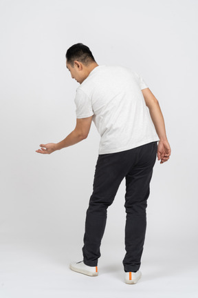Rear view of a man bending down with extended arm