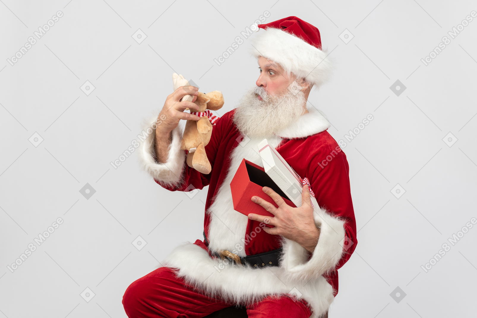 惊讶的圣诞老人看着鹿毛绒玩具