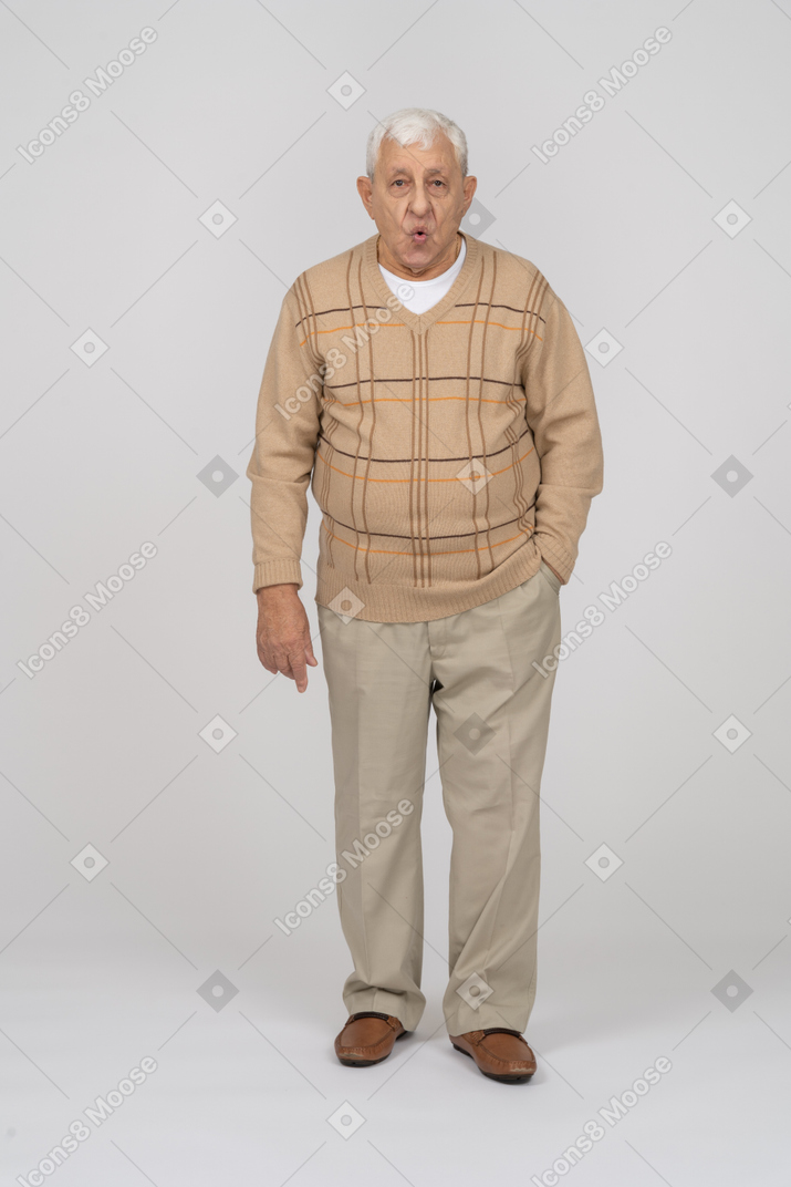 Front view of an old man in casual clothes standing with open mouth and looking at camera