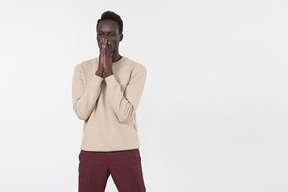 Un giovane uomo di colore in un maglione grigio in piedi da solo su sfondo bianco