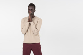 A young black man in a grey sweater standing alone on the white background