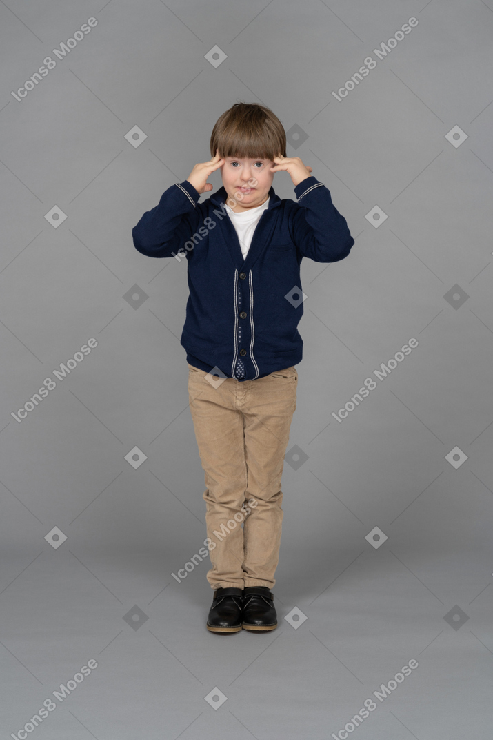 Retrato de un niño pequeño tocándose las sienes mientras se ve estresado