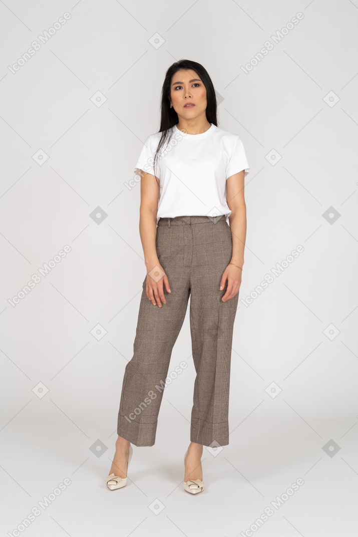 Front view of a perplexed young lady in breeches and t-shirt standing looking aside