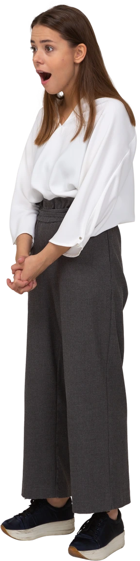 Three-quarter view of a shocked young lady in office clothing holding hands together
