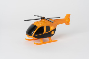 Hélicoptère jouet noir et orange debout sur un fond blanc